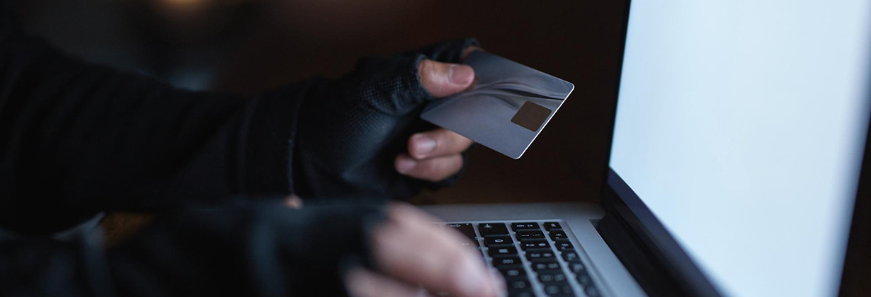 Um homem segurando cartão de crédito e usando laptop