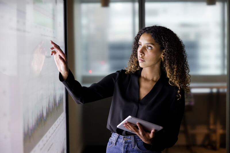 mulher segurando um tablet em frente a uma tela